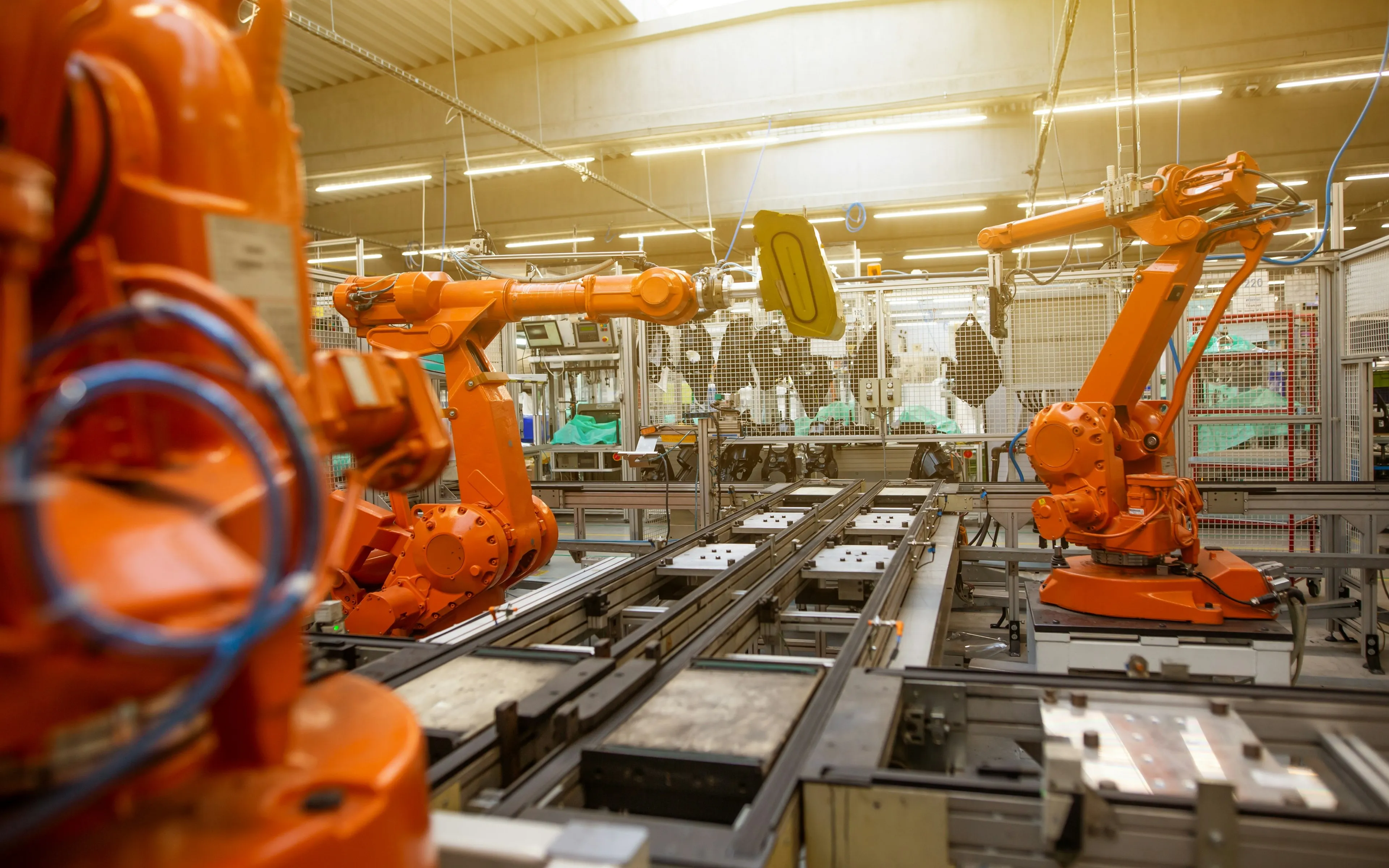 Bright orange robotic arms on an automated manufacturing line