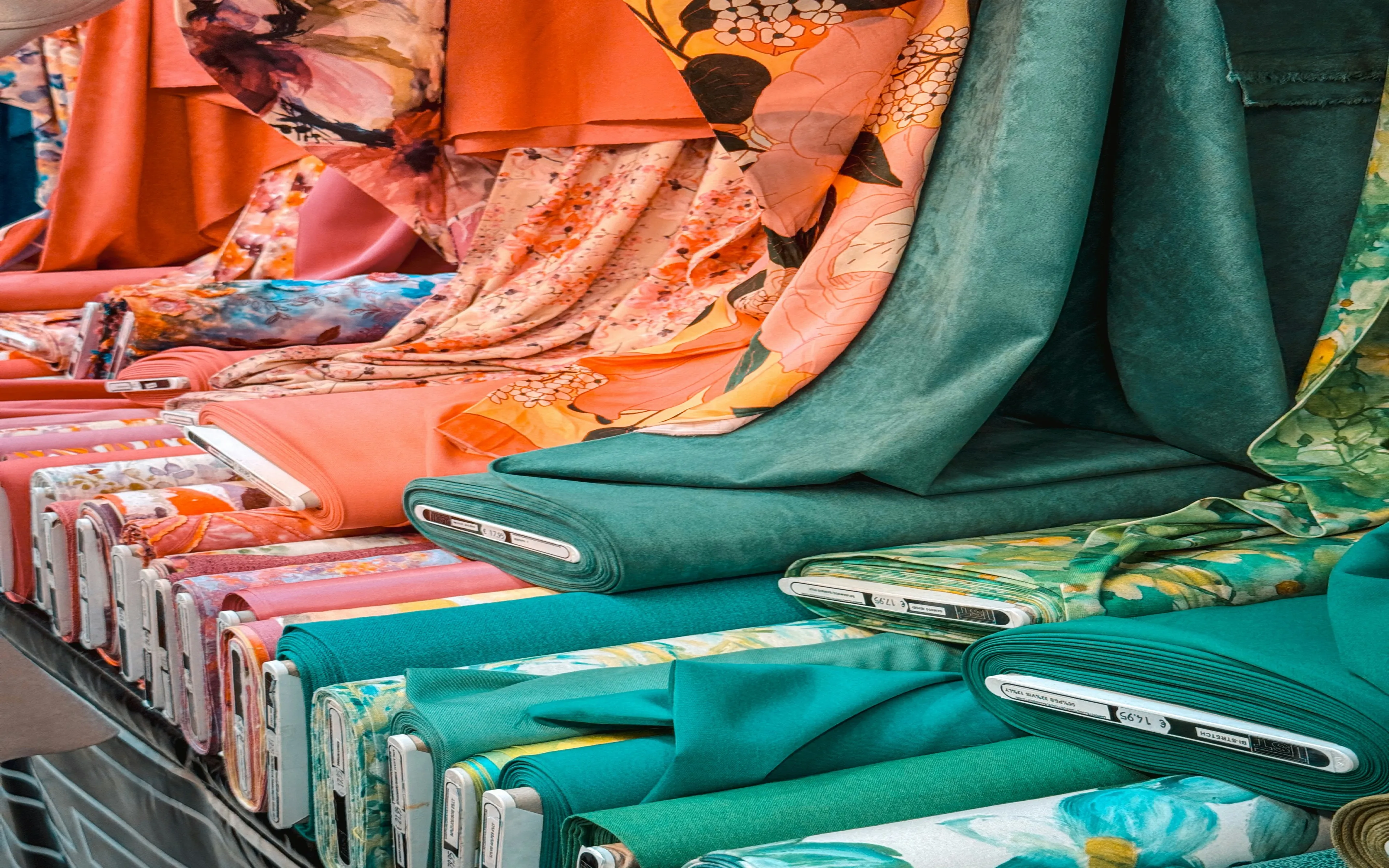 Colorful fabric rolls in coral, teal, and floral textiles